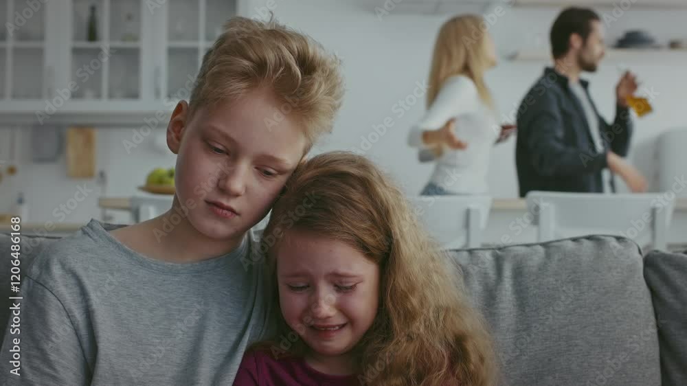 Two children closely embrace on a couch, showing fear and sadness as domestic violence unfolds in their home. Two children closely embrace on a couch, showing fear and sadness as domestic violence unfolds in their home.