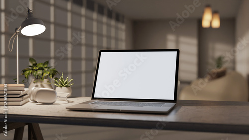 A laptop and decorative items on a desk in a room at nighttime, illuminated by a table lamp.
