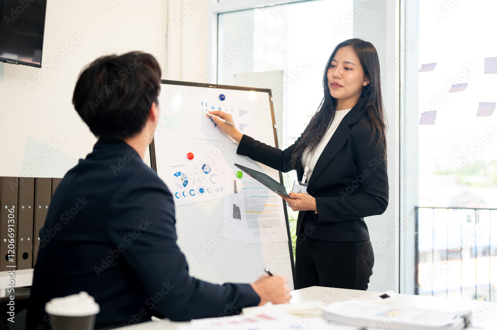 A confident, positive Asian businesswoman is presenting her project to her team in a meeting room. A confident, positive Asian businesswoman is presenting her project to her team in a meeting room.