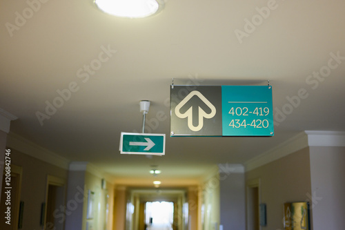 Hotel room sign on hotel ceiling and emergency exit sign. Room numbers, sign in hotel, hostel, apartment. Residential building for living, office rent, hotel room. photo