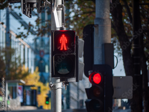 A red pedestrian traffic light signal with a modern LED display showing a red stop symbol—urban infrastructure and road safety systems in Melbourne Australia.