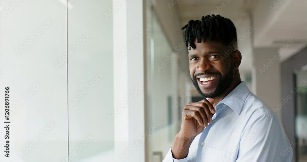 Smiling African American man in office wearing blue shirt, standing near glass wall, copy space Smiling African American man in office wearing blue shirt, standing near glass wall, copy space