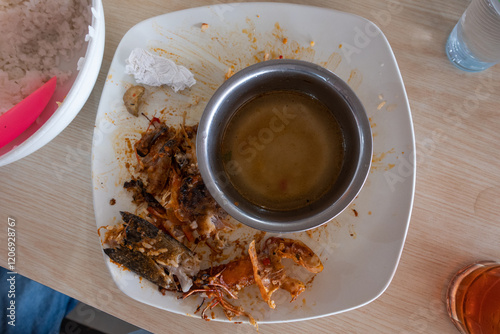 Top view of Empty Plate with Leftover Seafood and Sauce Indicating a Finished Meal