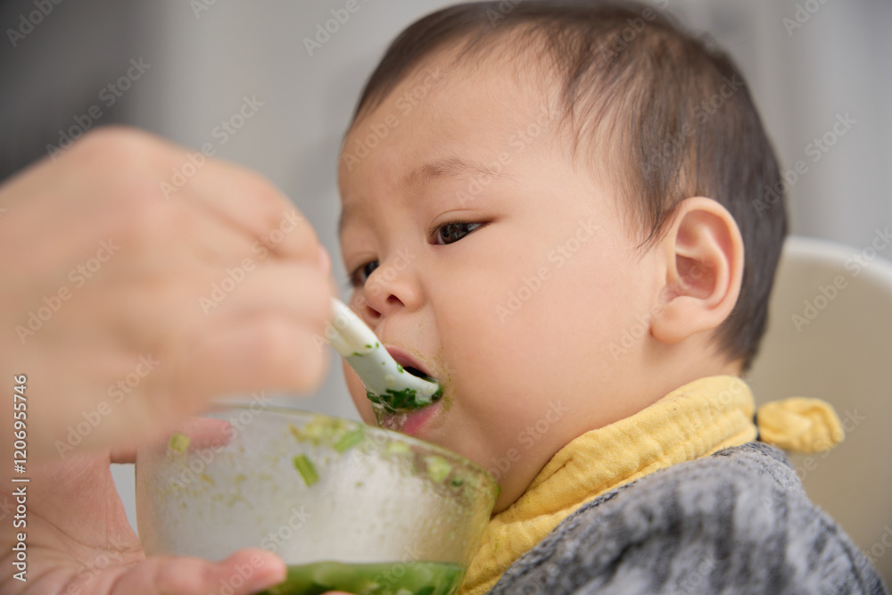 there is a baby eating from a bowl with a spoon there is a baby eating from a bowl with a spoon
