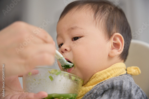 there is a baby eating from a bowl with a spoon