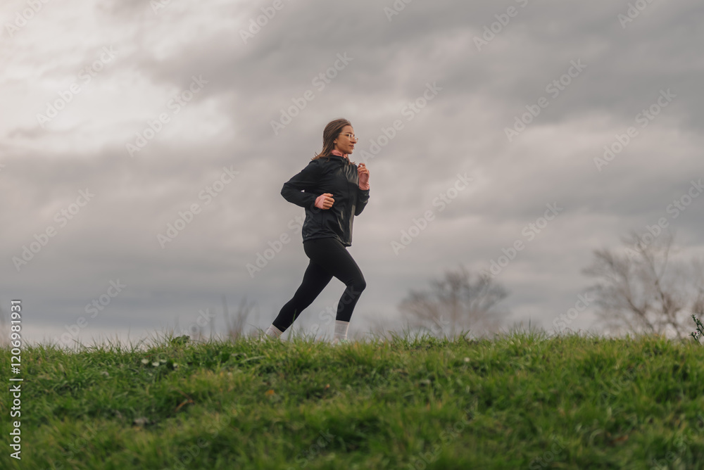 Woman running in a park on a cloudy day