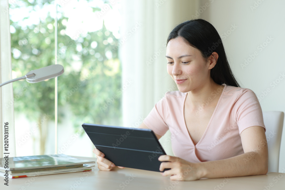 Asian woman watching media on tablet in a room Asian woman watching media on tablet in a room