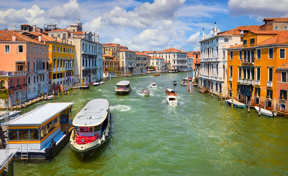 Grand Canal in Venice Italy. Panoramic view to picturesque landscape city with water transport traffic. Motorboats, vaporetto cutters on Sunny summer day blue sky clouds