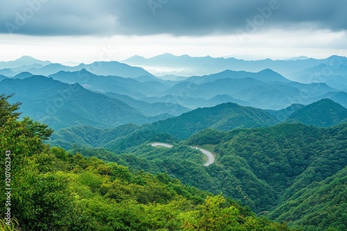 Scenic winding road through lush green mountains under a cloudy sky.