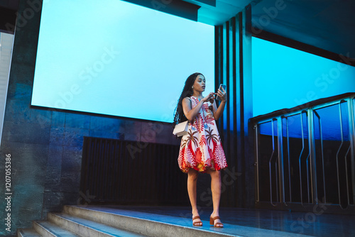 Woman using smart phone near projection screen on steps photo