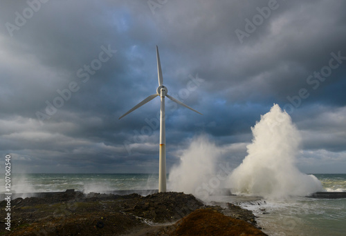 Windmill near splashing waves under stormy clouds photo