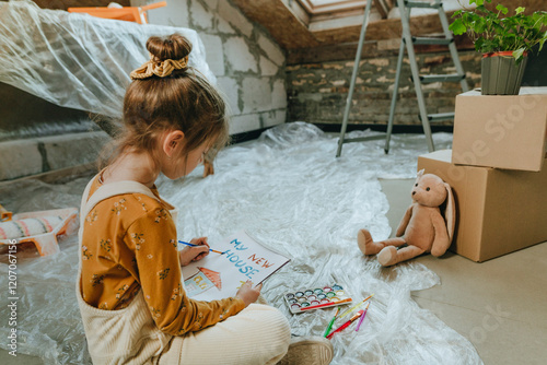 Girl painting house drawing on book sitting with teddy bear at home photo