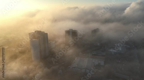 Aerial drone footage of circling around high-rise buildings in the morning mist at sunrise