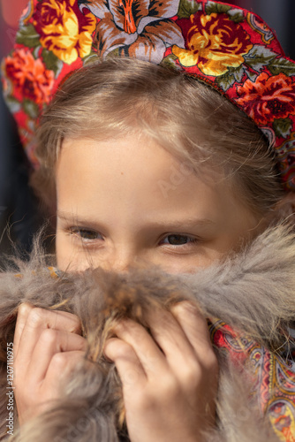 A blonde girl in a national Russian costume on the Maslenitsa holiday. A beautiful russian girl in a national costume made of a fur cape and kokoshnik. Close-up portrait