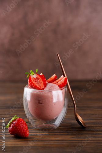 Whipped strawberry tofu and mousse dessert in a glass with spoon. Vegan food. Lactose and sugar free. Selective focus. Vertical orientation.