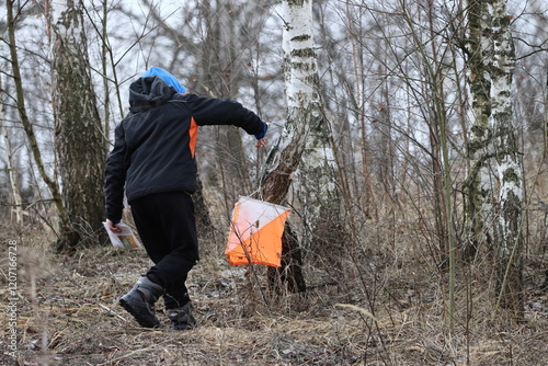 A boy training in orienteering at a checkpoint in a tree