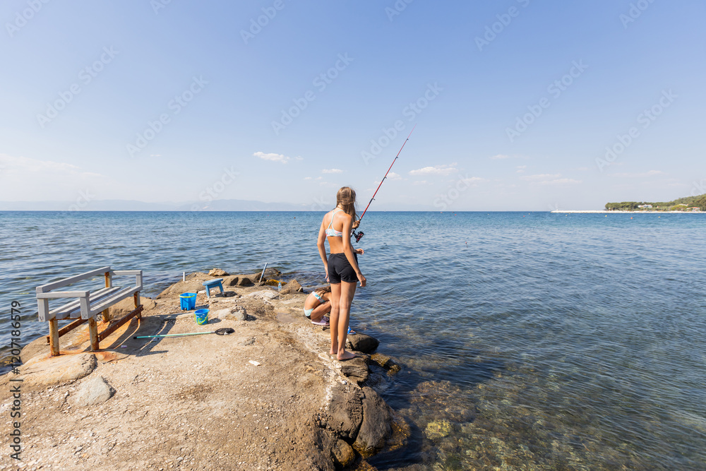 Children fishing on a rocky shore, gazing over the clear blue sea. Children fishing on a rocky shore, gazing over the clear blue sea.