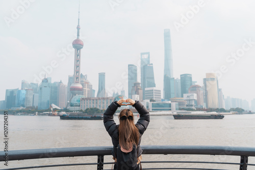 woman traveler visiting in Shanghai, China. Female Tourist with backpack sightseeing Shanghai view of Lujiazui in The Bund of Shanghai. landmark and popular for tourism attractions. Vacation concept photo