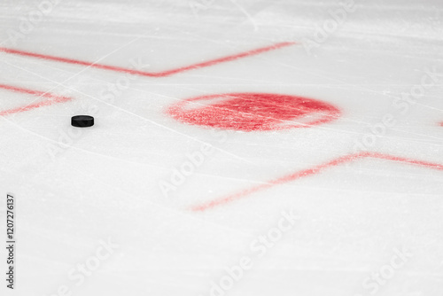 Fotografía Hockey puck on white ice close up near red circle at faceoff spot