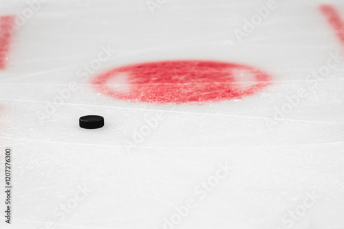 фотографія Hockey puck on white ice close up near red circle at faceoff spot