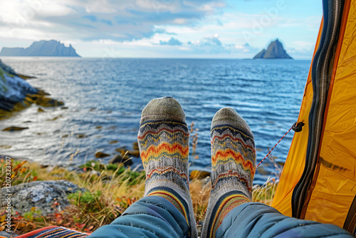 Legs in warm socks stick out of a tent against the backdrop of the sea. with the sound of the waves and the view of the water.