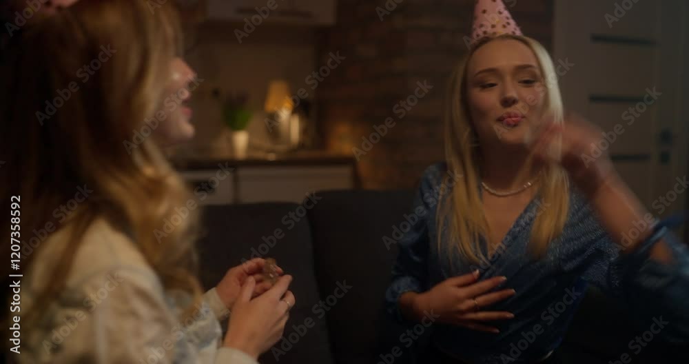 Happy girlfriends apply glitter to their faces and look at themselves in the mirror while preparing for a party at home in the evening Happy girlfriends apply glitter to their faces and look at themselves in the mirror while preparing for a party at home in the evening