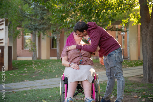 Couple sharing a kiss on a college campus, woman in wheelchair photo