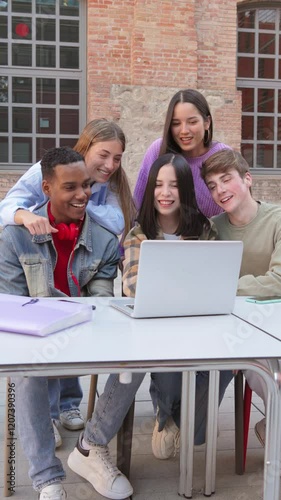 Vertical. Group of enthusiastic students gathered around a laptop, engaged in collaborative study session, sharing ideas and excitement, teamwork and learning among teenagers at university campus