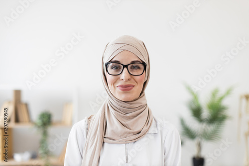 Canvas Print Portrait of a young Muslim woman doctor wearing hijab and glasses, exuding confidence and professionalism