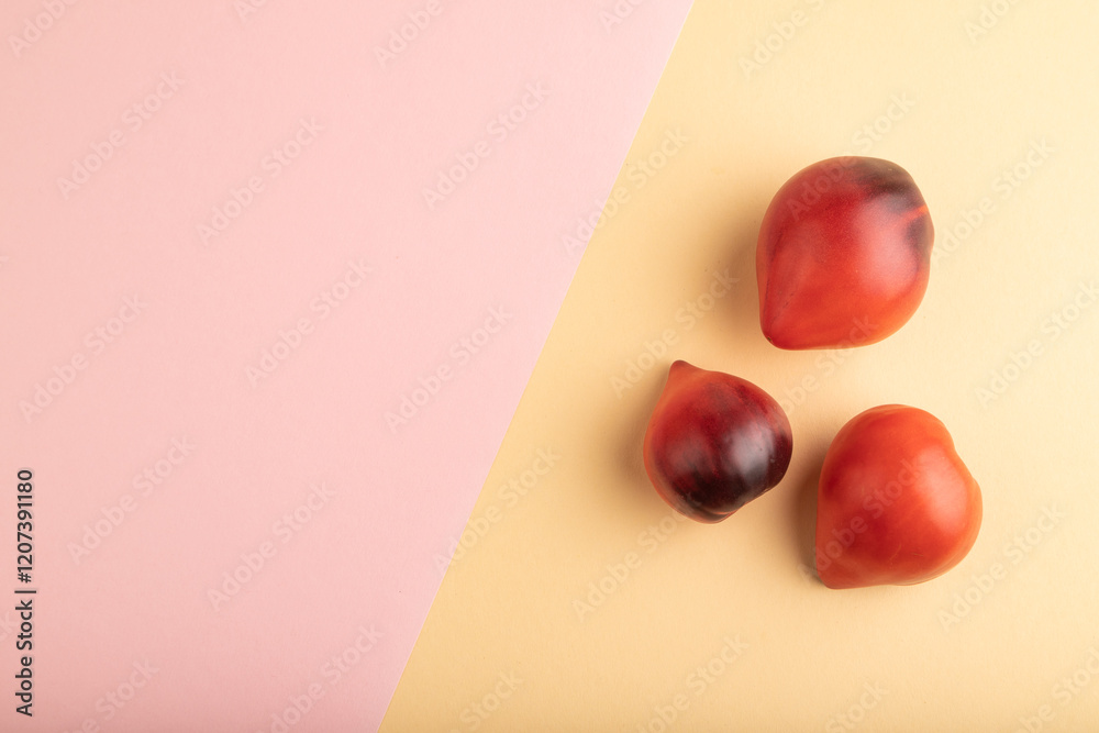 Red Heart shape tomatoes on pink and orange pastel paper. Top view, copy space Red Heart shape tomatoes on pink and orange pastel paper. Top view, copy space