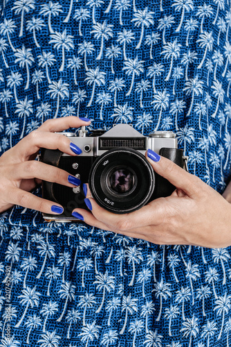 Woman wearing tropical dress holding vintage camera photo