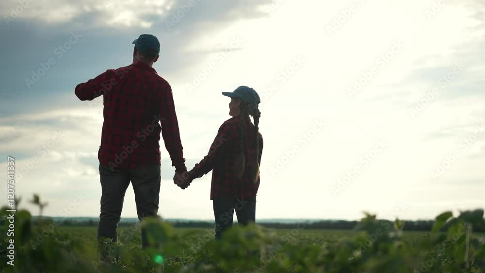 Family farmer in soybean field. Father and daughter hold hands in crop field at sunset. Learning about soybean farming. Farmer teaching family about crops. Family bonding over soybean farming. Family farmer in soybean field. Father and daughter hold hands in crop field at sunset. Learning about soybean farming. Farmer teaching family about crops. Family bonding over soybean farming.