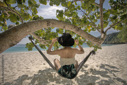 Sit in a hammock under a shady tree on the beach, looking at the sea view in the morning with good weather photo