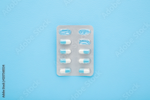 Used blister pack with pills on light blue table background. Pastel color. Closeup. Top down view.