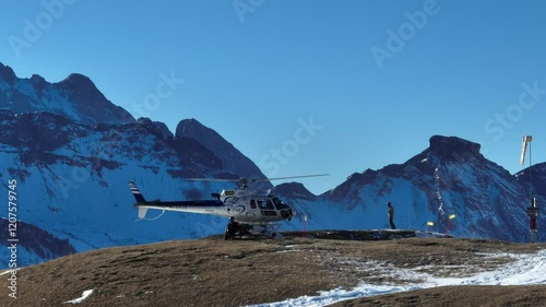 Helicopter on a snowy mountain helipad with a picturesque alpine backdrop. Helicopter, sightseeing flights over the Dolomites and Alps. Helicopter is standing on a landing field in the mountains. photo