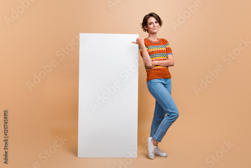 Full length photo of attractive person indicate finger empty space big smart phone screen isolated on beige color background photo