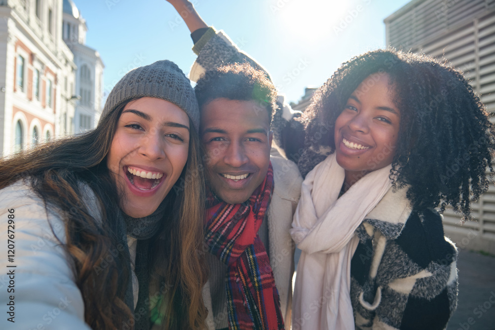Three happy multi ethnic friends are taking a selfie during a winter day in the city center