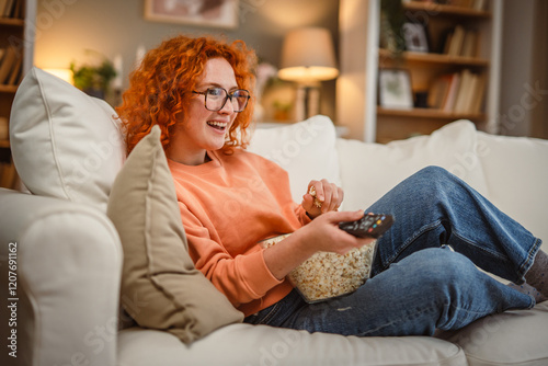 Fotografie happy adult woman watch movie on sofa and eat popcorn leisure activity