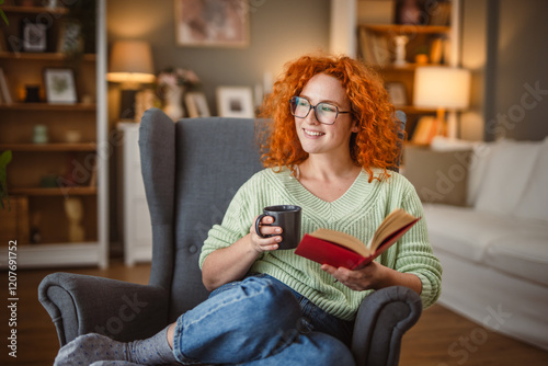 beauty redhead woman sit in the armchair and enjoy at coffee and book