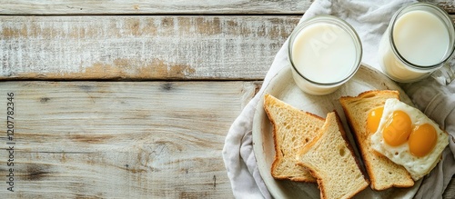 Breakfast plate with toast, fried eggs, and two glasses of milk on a wooden table with copy space for text photo