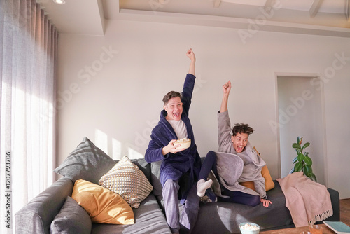 Happy gay couple cheering on sofa photo