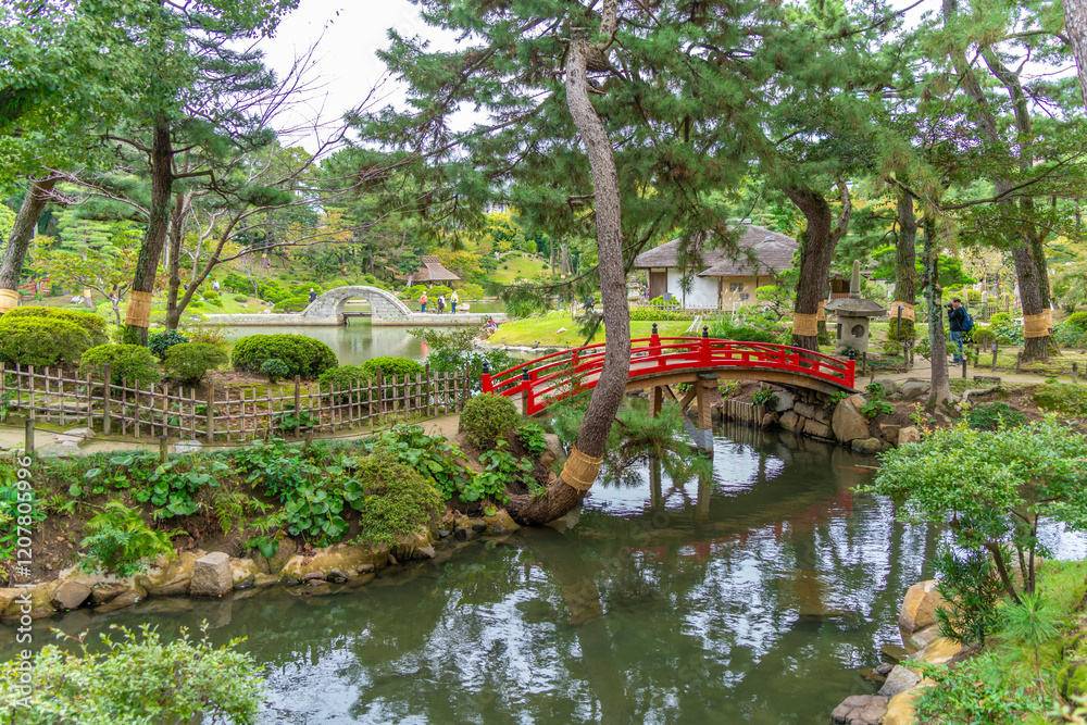 View of red footbridge over Takueichi Pond in Shukkeien Garden, Kaminoboricho, Naka Ward, Hiroshima, Honshu, Japan View of red footbridge over Takueichi Pond in Shukkeien Garden, Kaminoboricho, Naka Ward, Hiroshima, Honshu, Japan