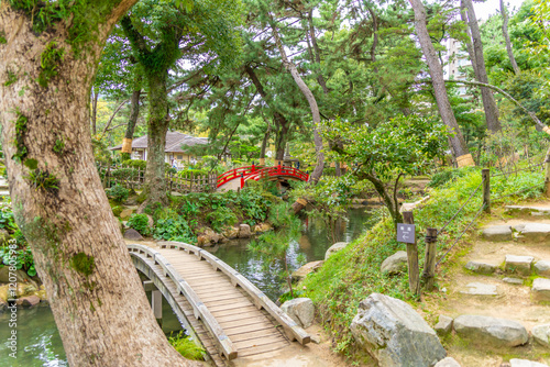 View of red footbridge over Takueichi Pond in Shukkeien Garden, Kaminoboricho, Naka Ward, Hiroshima, Honshu, Japan photo