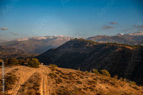 Sunset over arid hilly landscape in front of the snowy Sierra Nevada, Albaicin, Granada, Andalucia, Spain photo