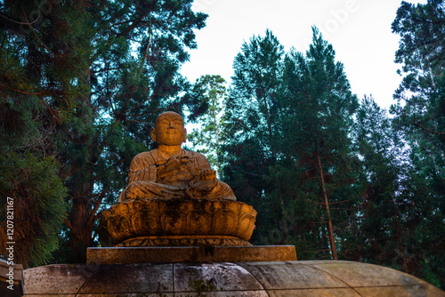 Seated Buddha statue in deep forest of Koyasan at dusk, Buddhist cemetery of Oku-no-in, Koyasan (Koya-san), Kansai, Honshu, Japan photo