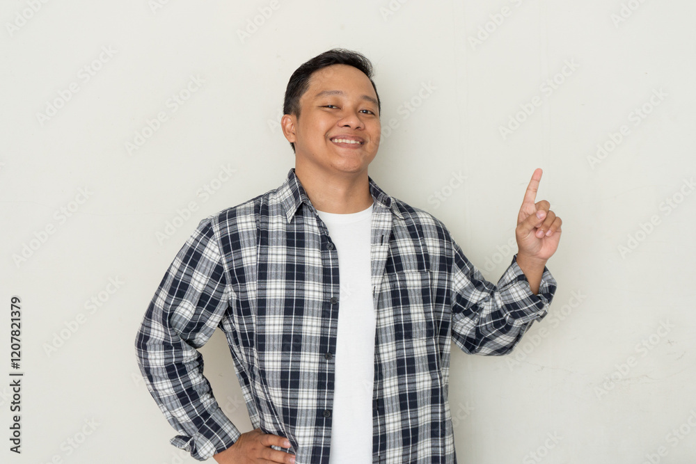 Attractive young Asian man smiling and pointing his finger to the side. Copy space. Attractive young Asian man smiling and pointing his finger to the side. Copy space.