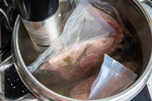 Thermal immersion circulator and vacuum packed meat in pot on white background. Sous vide cooking