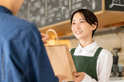 Fotografía テイクアウト商品を顧客に渡すカフェ店員