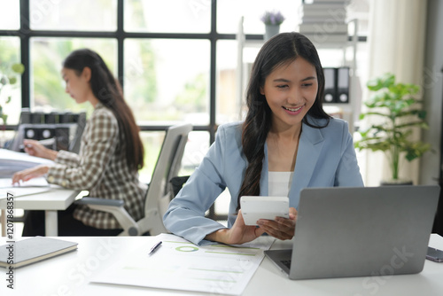 Young professional woman calculating financial data and working on laptop in modern office