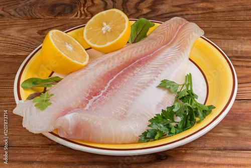Pangasius fillet on yellow dish with lemon on rustic table